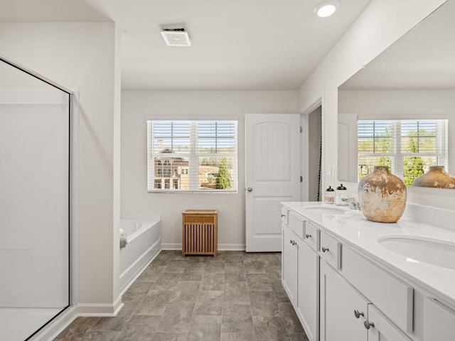 bathroom with a stall shower, a garden tub, baseboards, and double vanity