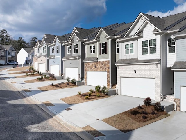 multi unit property with a residential view, a garage, driveway, and stone siding