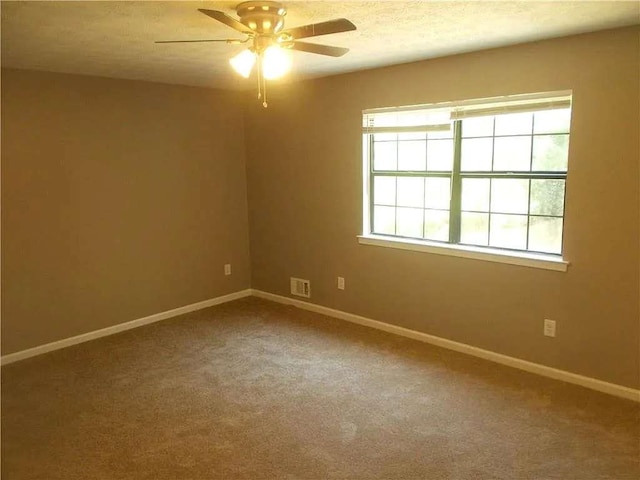 empty room with a ceiling fan, baseboards, carpet flooring, and visible vents