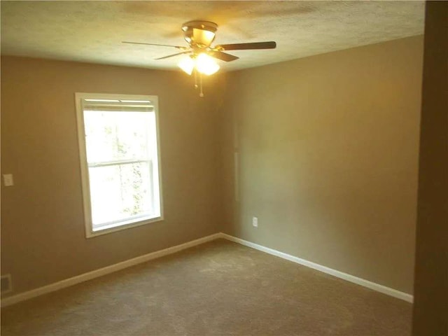 empty room featuring carpet flooring, a wealth of natural light, baseboards, and a ceiling fan