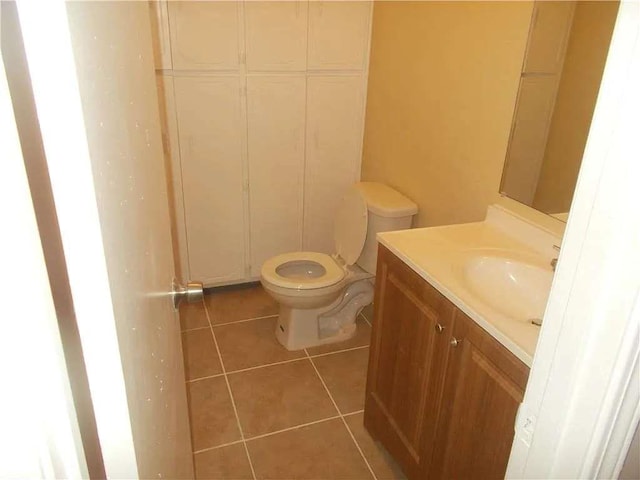 half bathroom with toilet, tile patterned flooring, and vanity