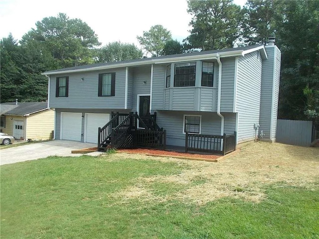 raised ranch featuring a garage, a front lawn, a chimney, and driveway