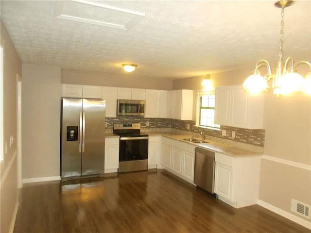 kitchen featuring stainless steel appliances, a textured ceiling, white cabinets, and tasteful backsplash