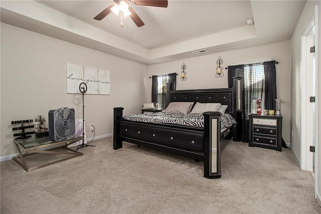 bedroom featuring a raised ceiling, ceiling fan, and carpet