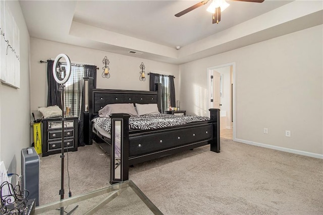 carpeted bedroom featuring a raised ceiling and ceiling fan