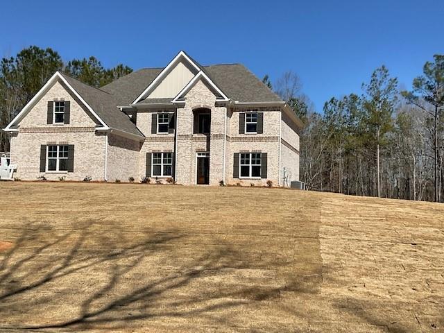 view of front of house with a front yard, central AC unit, and brick siding