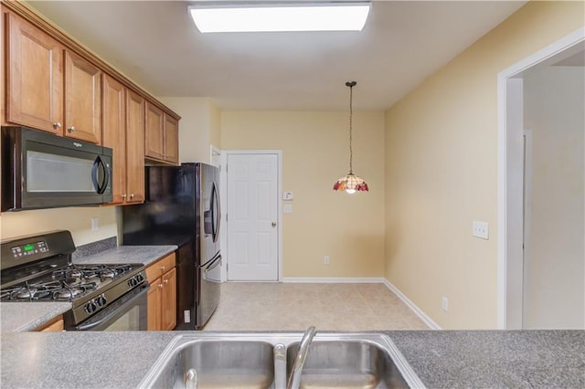 kitchen featuring brown cabinetry, baseboards, a sink, black appliances, and decorative light fixtures