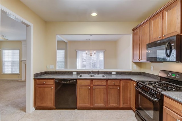 kitchen featuring brown cabinets, a notable chandelier, black appliances, a sink, and dark countertops