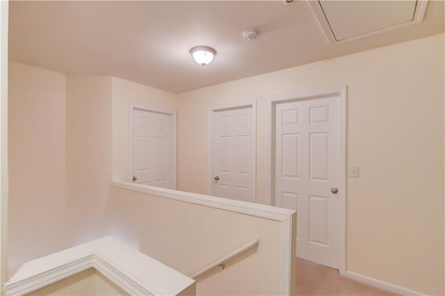 corridor with baseboards, an upstairs landing, and light colored carpet