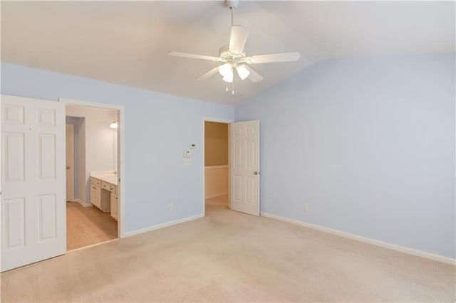 unfurnished bedroom featuring baseboards, ceiling fan, vaulted ceiling, light carpet, and connected bathroom