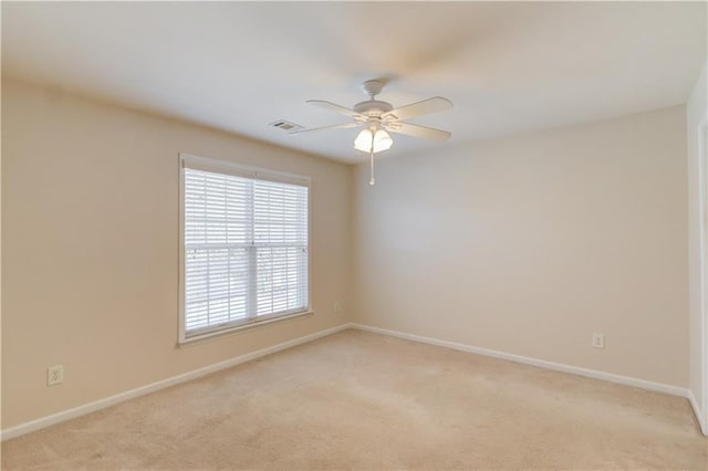 spare room with ceiling fan, baseboards, visible vents, and light carpet