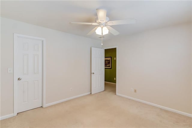 spare room featuring baseboards, light carpet, and ceiling fan