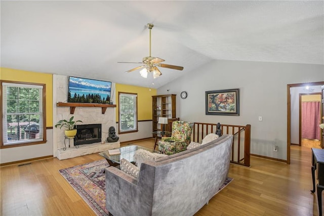 living room featuring a fireplace, light wood-type flooring, ceiling fan, and lofted ceiling