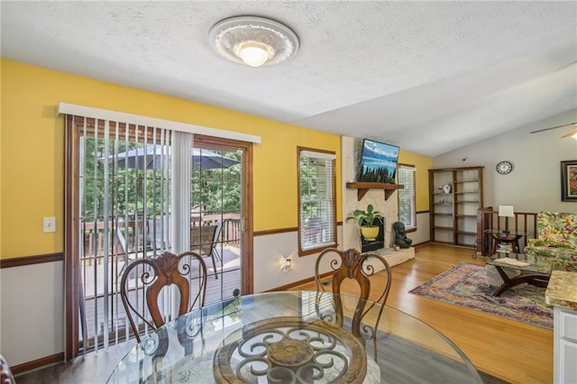 dining area with a textured ceiling, hardwood / wood-style flooring, and vaulted ceiling