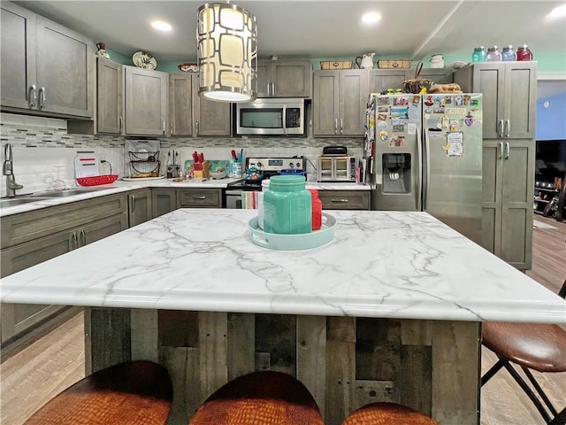 kitchen with a center island, hanging light fixtures, stainless steel appliances, a kitchen breakfast bar, and light hardwood / wood-style floors