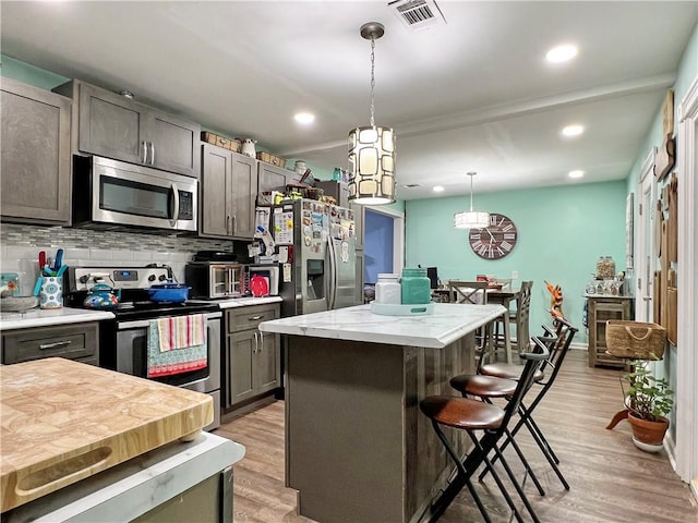 kitchen featuring a center island, hanging light fixtures, light wood-type flooring, and appliances with stainless steel finishes