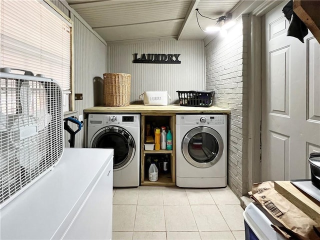 laundry room featuring washing machine and dryer, wood walls, and light tile patterned floors