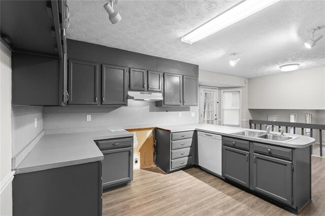 kitchen with dishwasher, sink, gray cabinets, light wood-type flooring, and kitchen peninsula