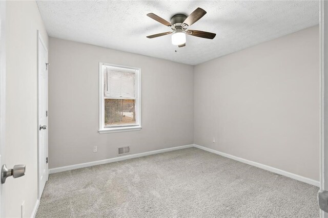 spare room featuring light carpet, a textured ceiling, and ceiling fan