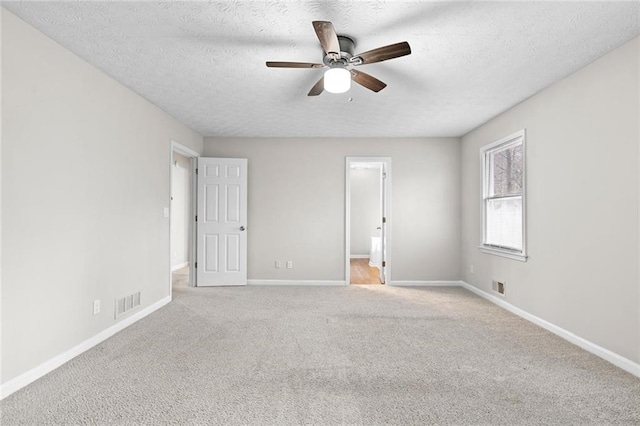 carpeted spare room featuring ceiling fan and a textured ceiling