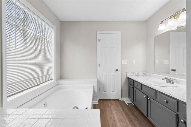 bathroom with hardwood / wood-style flooring, vanity, and a tub