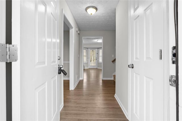 corridor featuring wood-type flooring and a textured ceiling