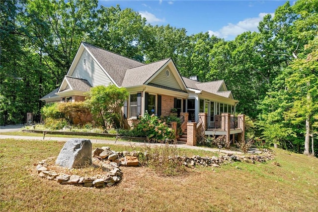 view of front of home with a front lawn, brick siding, a shingled roof, and stairs