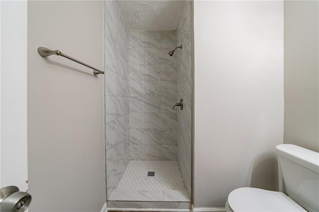 bathroom featuring a tile shower and toilet