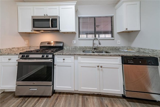 kitchen with appliances with stainless steel finishes, white cabinetry, and sink