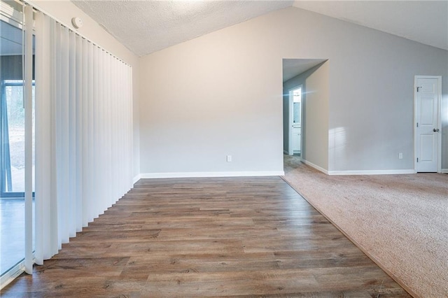 unfurnished room featuring a textured ceiling, lofted ceiling, and hardwood / wood-style flooring