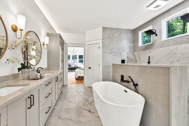2335 Flat Stone Dr, Cumming, GA 30041 - bathroom featuring a sink, tile walls, marble finish floor, a soaking tub, and double vanity