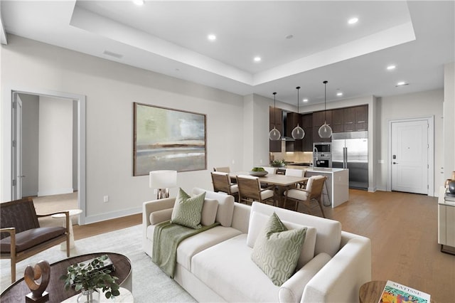 living room with light hardwood / wood-style flooring and a raised ceiling