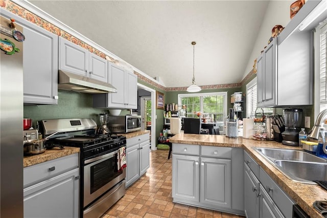 kitchen featuring stainless steel appliances, hanging light fixtures, gray cabinetry, a sink, and under cabinet range hood