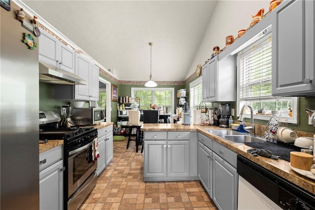 kitchen with hanging light fixtures, stainless steel appliances, gray cabinetry, under cabinet range hood, and a sink