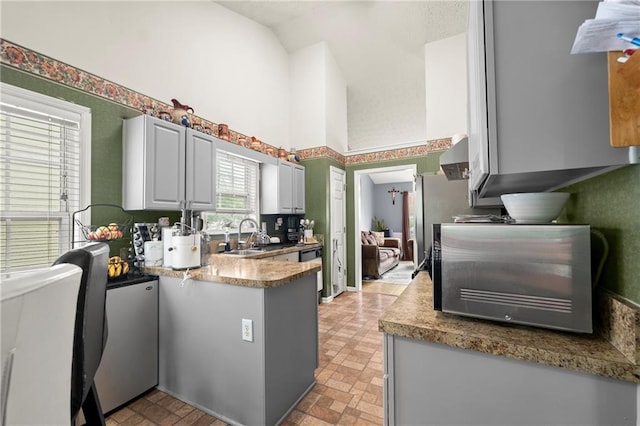 kitchen with high vaulted ceiling, gray cabinets, a sink, and dishwashing machine