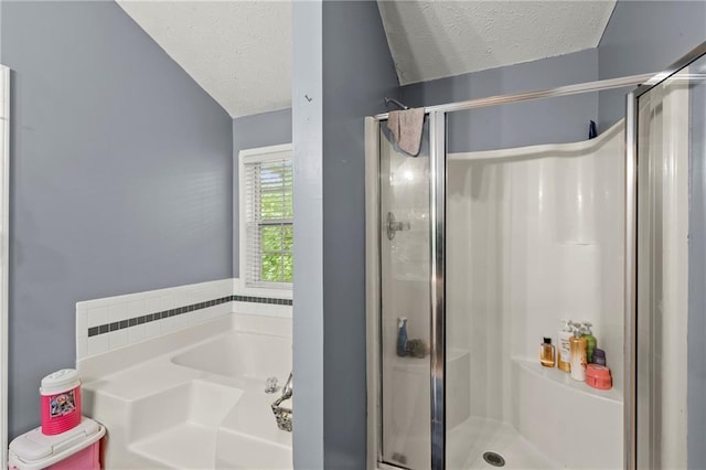 bathroom with a shower stall, a textured ceiling, and a bath