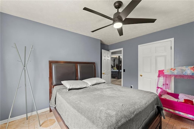 bedroom featuring a ceiling fan, a walk in closet, a textured ceiling, and baseboards