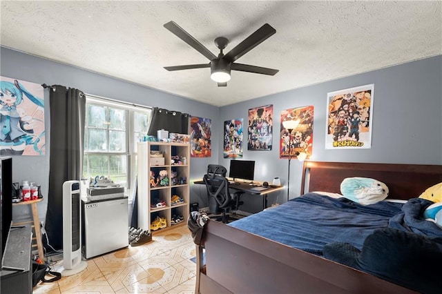 bedroom with a ceiling fan, freestanding refrigerator, and a textured ceiling