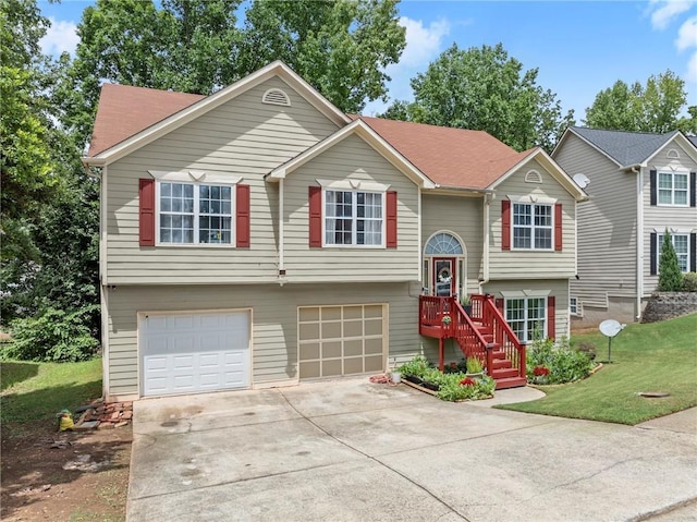 bi-level home featuring a garage, concrete driveway, and a front yard