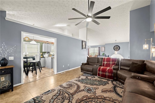 living room with a textured ceiling, light tile patterned floors, a ceiling fan, baseboards, and vaulted ceiling