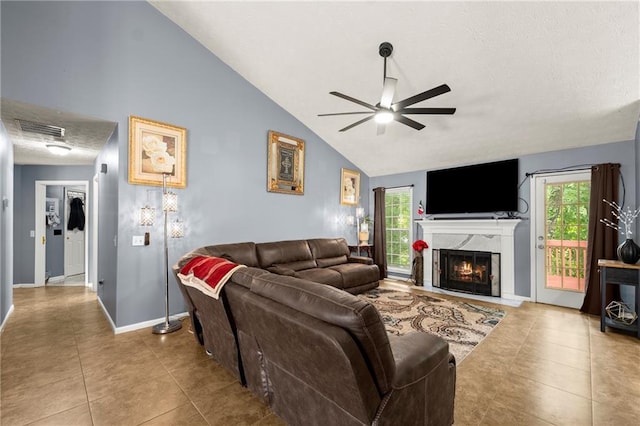 living room with a ceiling fan, a wealth of natural light, visible vents, and a lit fireplace