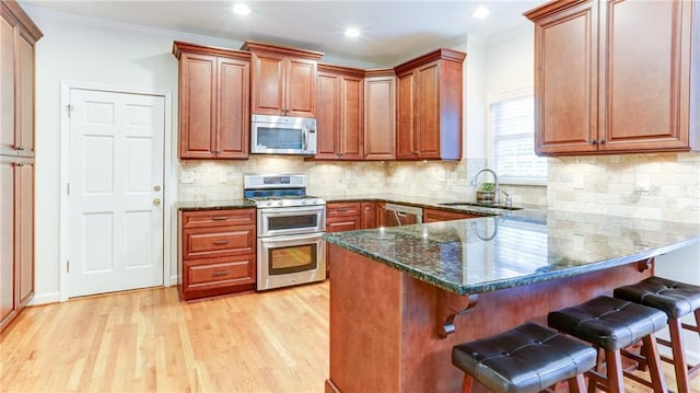 251 Waterford Cove Dr, Suwanee, GA 30024 - kitchen featuring stainless steel appliances, a sink, a kitchen breakfast bar, dark stone countertops, and a peninsula