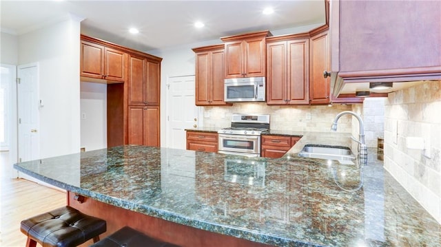 251 Waterford Cove Dr, Suwanee, GA 30024 - kitchen featuring appliances with stainless steel finishes, a sink, a peninsula, crown molding, and dark stone counters