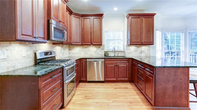 251 Waterford Cove Dr, Suwanee, GA 30024 - kitchen featuring appliances with stainless steel finishes, a peninsula, a sink, light wood finished floors, and a breakfast bar