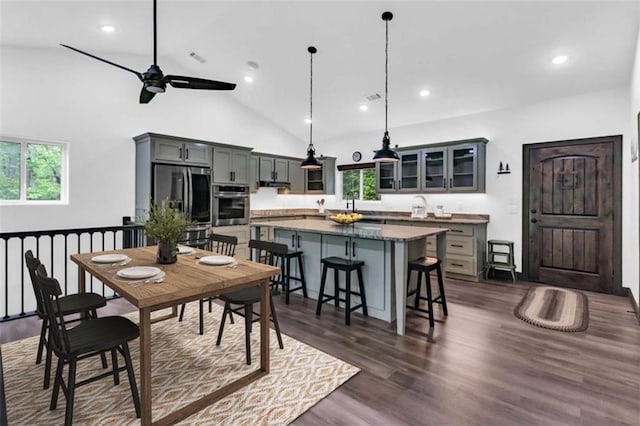 dining area with healthy amount of natural light, a ceiling fan, dark wood-style floors, recessed lighting, and high vaulted ceiling