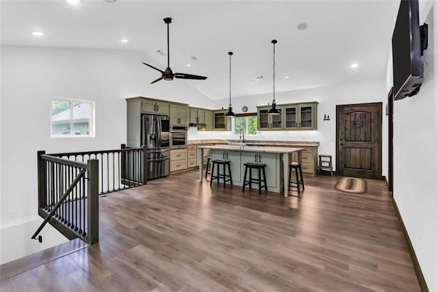 kitchen featuring stainless steel appliances, a kitchen bar, recessed lighting, light countertops, and a sink
