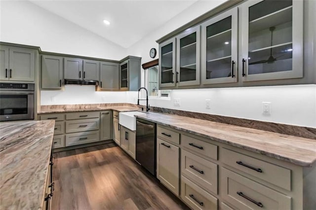 kitchen with oven, a sink, dishwashing machine, lofted ceiling, and light stone counters