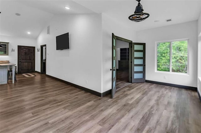 unfurnished living room with baseboards, wood finished floors, vaulted ceiling, and recessed lighting
