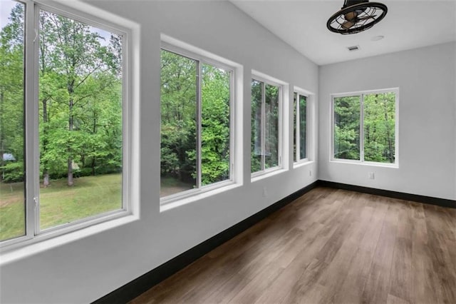 unfurnished sunroom featuring plenty of natural light, wood finished floors, and baseboards