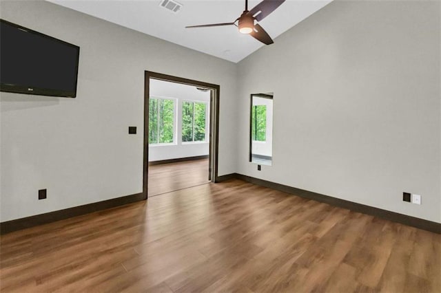 spare room featuring wood finished floors, baseboards, ceiling fan, and high vaulted ceiling